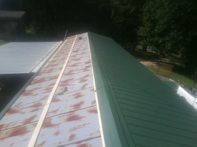 Old rusted panels beside newly installed green metal roofing — Wind Damage Roof Repair by Roofing Brothers in Sandwich