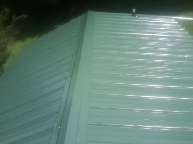 New green metal panels meeting at the ridge of a roof — Flat Roof Repair work by our crew in Sandwich