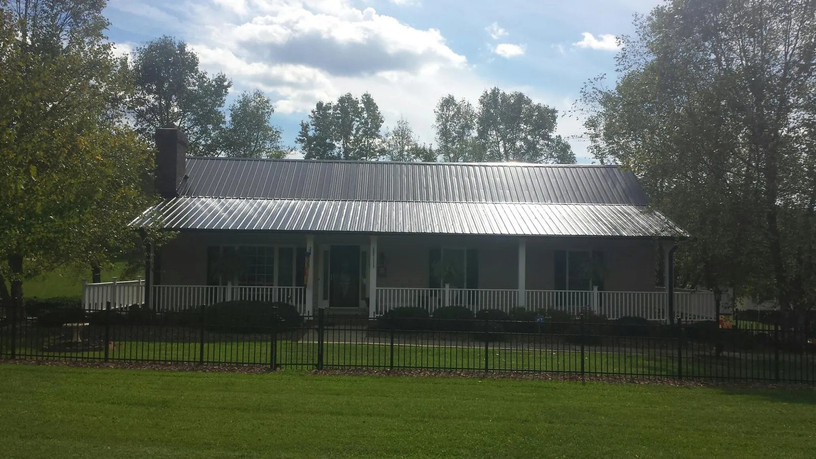 Gray metal roof on a brick ranch with a full width front porch — Gutter Guard Installation work by our crew in Sandwich